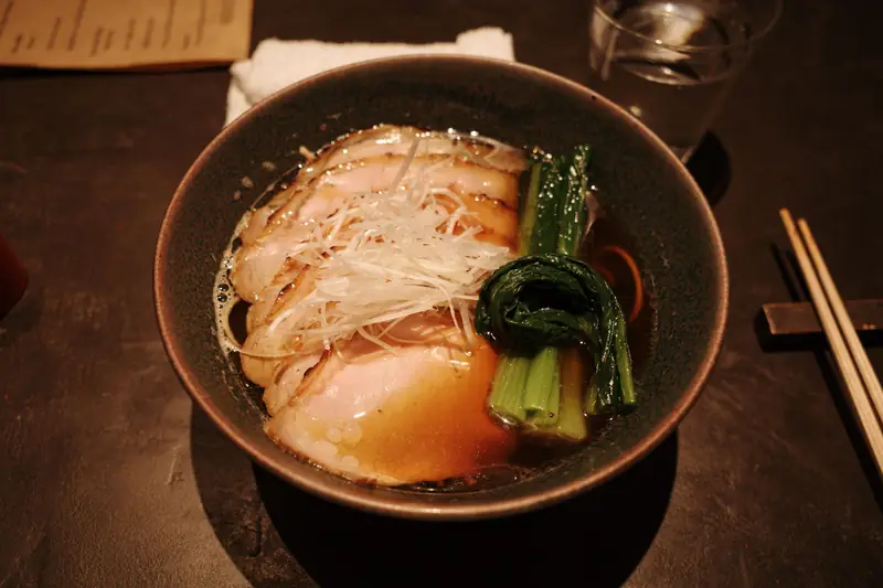 A bowl of ramen with pork slices and greens at a Kyoto restaurant
